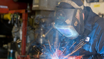 Welder with hood on creating sparks.